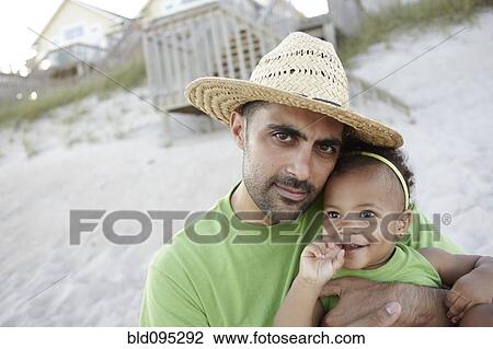 Father holding daughter on beach View Large Photo Image Stock Image - Father holding daughter on beach. Fotosearch