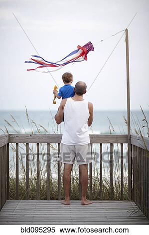 Stock Photography - Father holding son on deck near ocean. Fotosearch