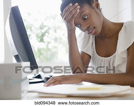 Stock Photo - Frustrated Black businesswoman working at desk. Fotosearch