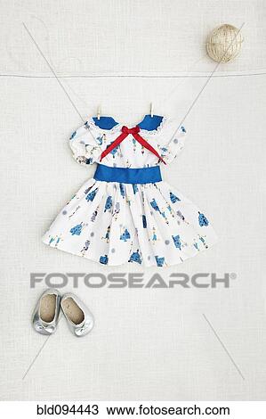 Stock Image - Girl's dress and shoes hanging on wall. Fotosearch