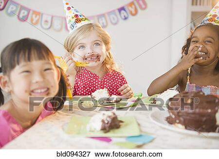 Stock Photo - Girls enjoying cake at birthday party. Fotosearch