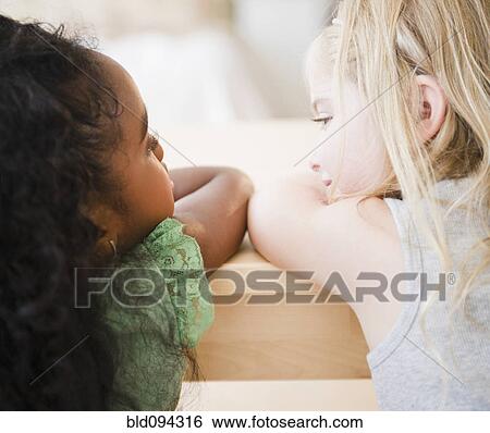 Stock Photograph - Girls leaning on table together. Fotosearch