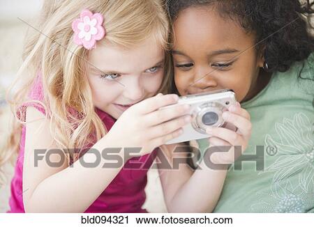 Stock Image - Girls looking at digital camera together. Fotosearch