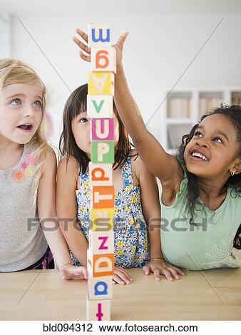 Stock Image - Girls stacking alphabet blocks together. Fotosearch