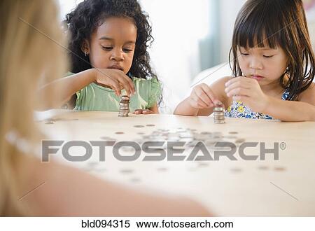 Stock Photography - Girls stacking coins together. Fotosearch