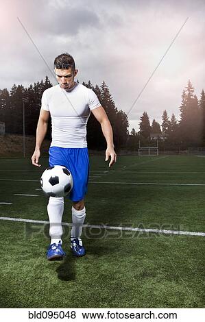 Stock Photo - Hispanic athlete kicking soccer ball. Fotosearch
