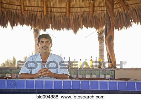 Stock Photo - Hispanic bartender standing behind bar. Fotosearch