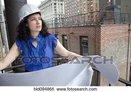 Stock Photography - Hispanic businesswoman reviewing blueprints. Fotosearch