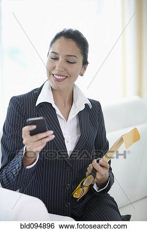 Hispanic businesswoman text messaging on cell phone View Large Photo Image Stock Photograph - Hispanic businesswoman text messaging on cell phone. Fotosearch