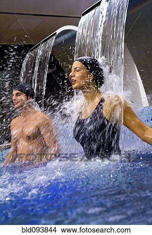 Picture - Hispanic couple enjoying waterfall in swimming pool. Fotosearch