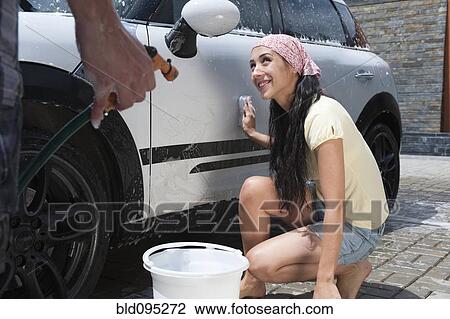 Stock Image - Hispanic couple washing car together. Fotosearch