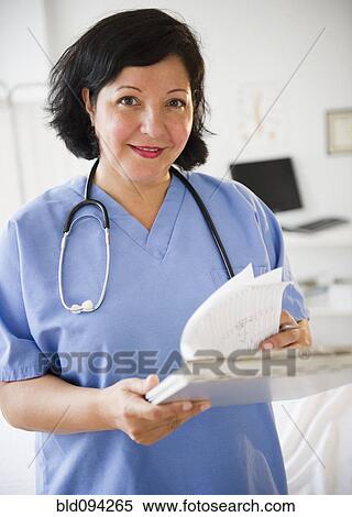 Stock Photography - Hispanic doctor looking at medical chart. Fotosearch