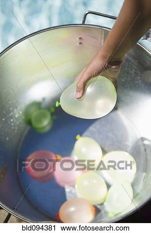 Hispanic girl picking water balloon out of bucket View Large Photo Image Stock Image - Hispanic girl picking water balloon out of bucket. Fotosearch