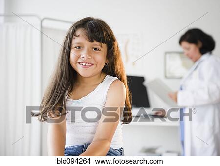 Picture - Hispanic girl sitting in doctor's office. Fotosearch