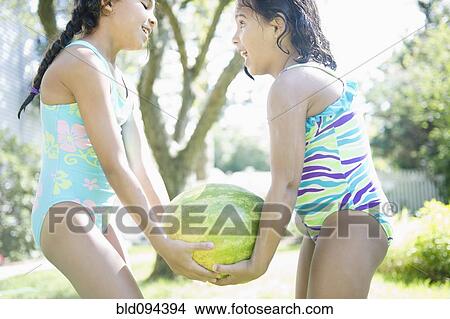 Picture - Hispanic girls carrying watermelon together. Fotosearch