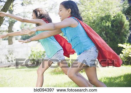 Stock Photo - Hispanic girls in capes playing superheroes. Fotosearch