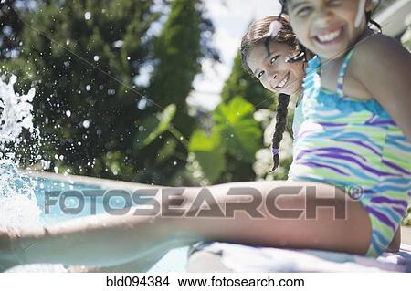 Picture - Hispanic girls sitting on edge of swimming pool. Fotosearch