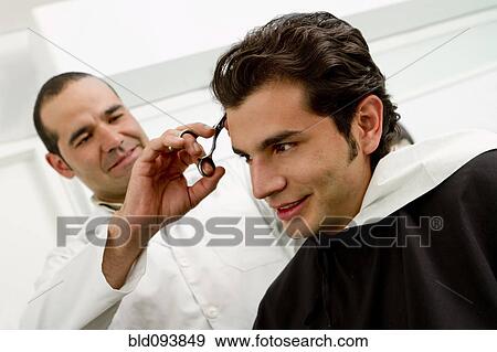 Stock Photo - Hispanic man having hair cut in barber shop. Fotosearch