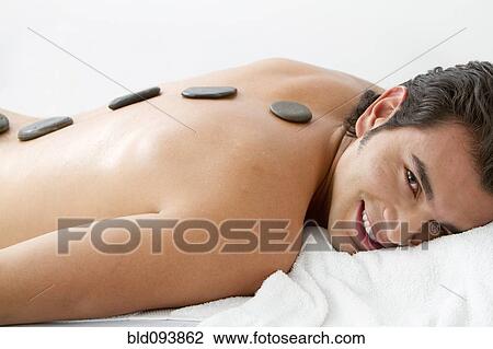 Stock Image - Hispanic man having hot stone therapy. Fotosearch