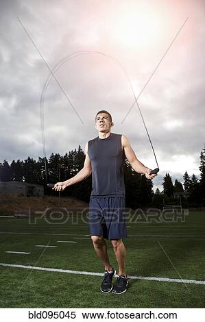 Stock Photography - Hispanic man jumping rope on field. Fotosearch
