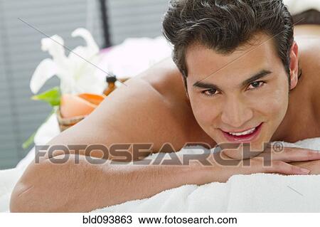 Stock Image - Hispanic man laying on massage table. Fotosearch