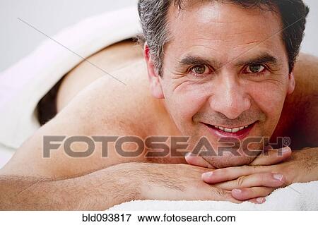 Stock Photo - Hispanic man laying on massage table. Fotosearch