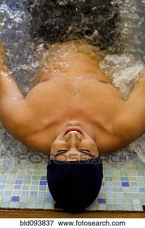 Stock Photo - Hispanic man soaking in hot tub. Fotosearch
