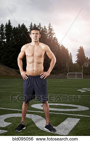 Stock Photograph - Hispanic man standing on football field. Fotosearch
