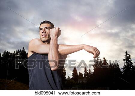 Stock Image - Hispanic man stretching before exercise. Fotosearch
