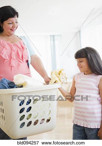 Stock Photo - Hispanic mother and daughter doing laundry. Fotosearch