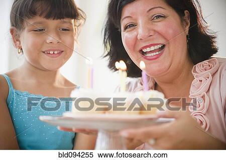 Stock Photography - Hispanic mother and daughter holding cupcakes. Fotosearch