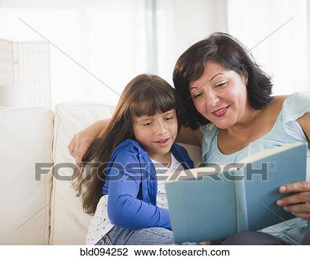 Stock Image - Hispanic mother and daughter reading a book. Fotosearch