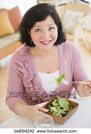 Stock Image - Hispanic woman eating salad for lunch. Fotosearch