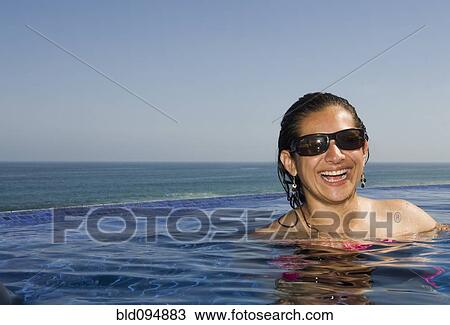 Stock Image - Hispanic woman enjoying swimming pool. Fotosearch