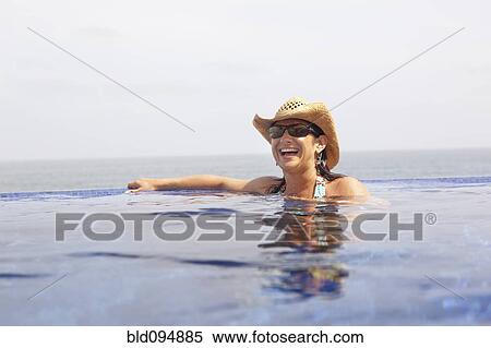 Stock Photography - Hispanic woman enjoying swimming pool. Fotosearch