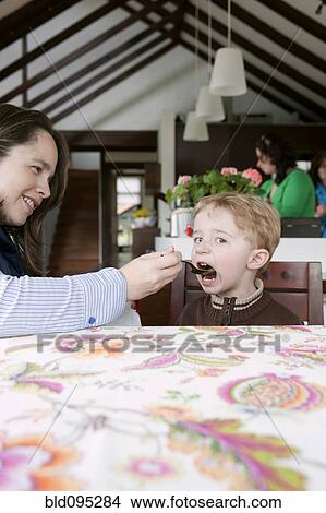 Picture - Hispanic woman feeding son. Fotosearch