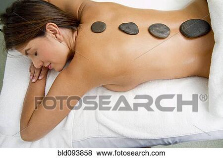 Stock Photo - Hispanic woman having hot stone therapy. Fotosearch