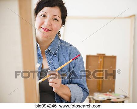 Stock Photograph - Hispanic woman painting on canvas. Fotosearch