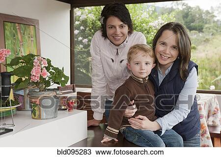Stock Image - Hispanic women hugging boy on porch. Fotosearch