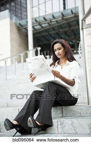 Picture - Indian businesswoman reading newspaper outdoors. Fotosearch