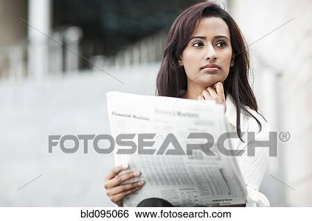 Stock Photograph - Indian businesswoman reading newspaper outdoors. Fotosearch