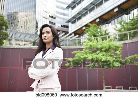 Stock Image - Indian businesswoman standing outdoors with arms crossed. Fotosearch