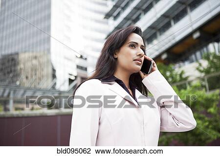 Stock Image - Indian businesswoman talking on cell phone. Fotosearch