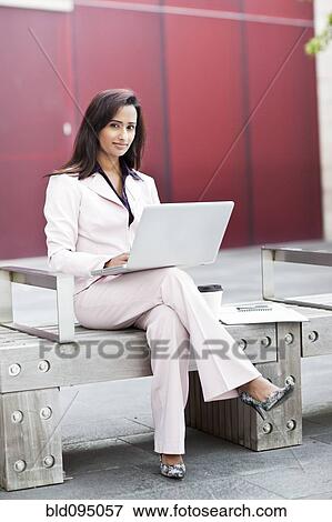 Stock Photo - Indian businesswoman using laptop on bench. Fotosearch