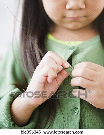 Stock Photograph - Korean girl buttoning sweater. Fotosearch