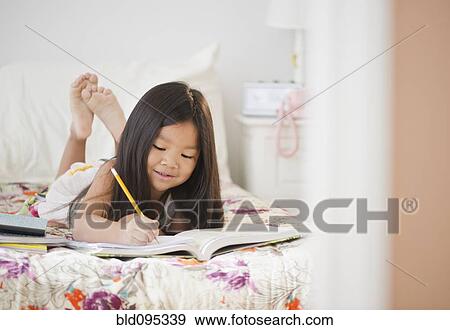 Korean girl doing homework on bed View Large Photo Image Stock Photo - Korean girl doing homework on bed. Fotosearch