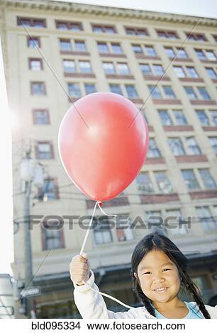 Picture - Korean girl holding red balloon outdoors. Fotosearch