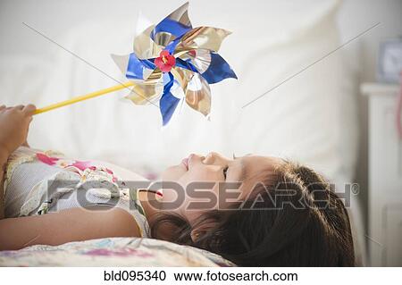 Korean girl laying on bed holding pinwheel View Large Photo Image Stock Image - Korean girl laying on bed holding pinwheel. Fotosearch