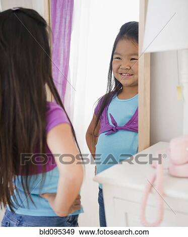 Stock Photo - Korean girl looking at reflection in mirror. Fotosearch