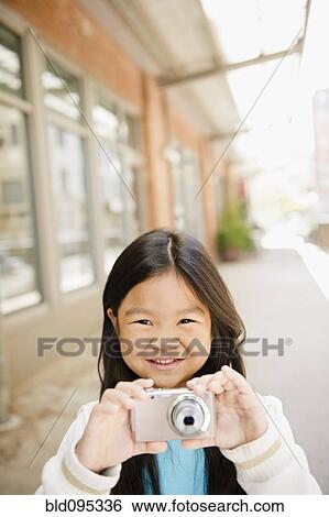 Stock Photograph - Korean girl taking photographs with digital camera. Fotosearch
